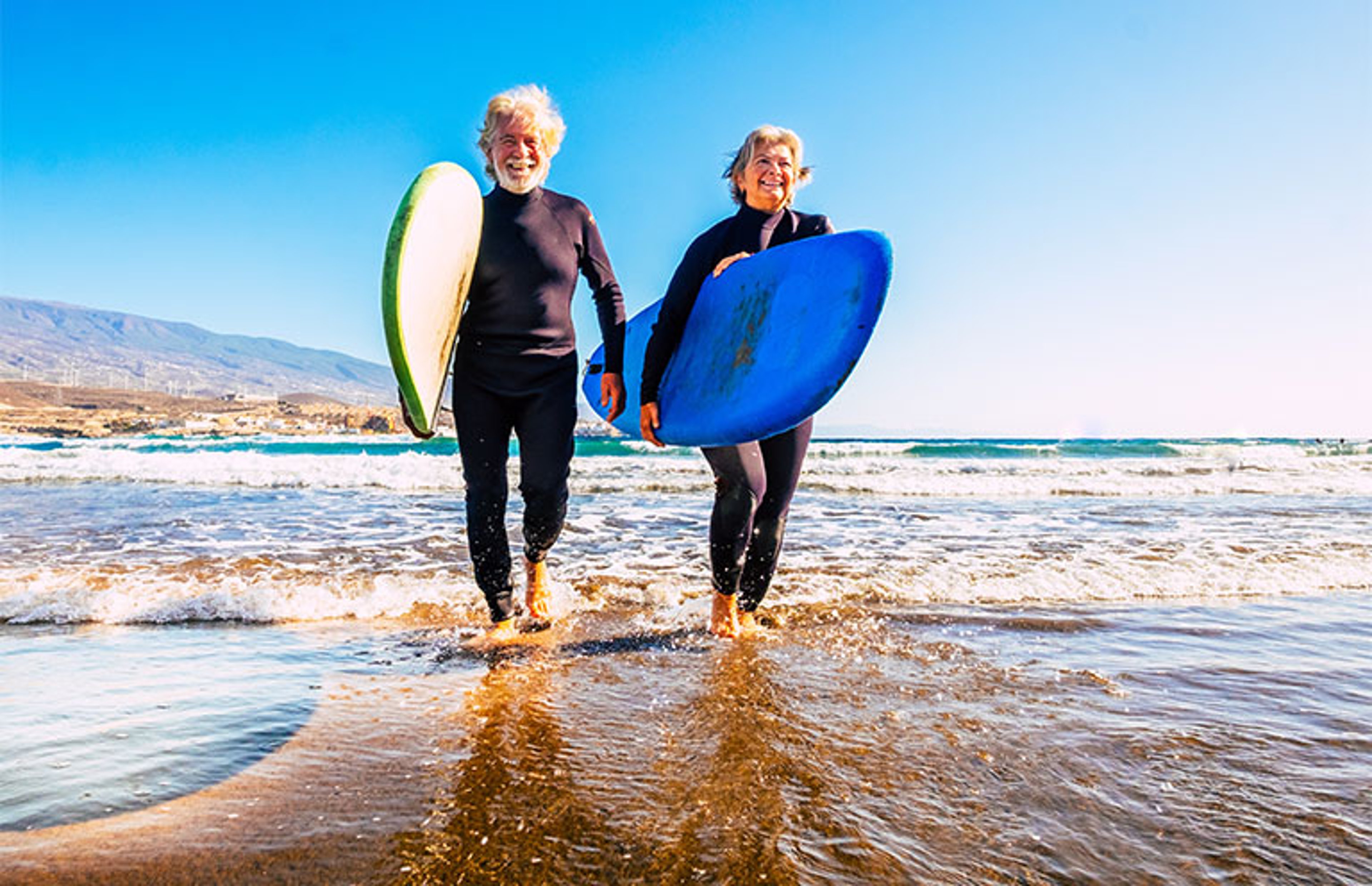 elder couple with surf boards at the beach