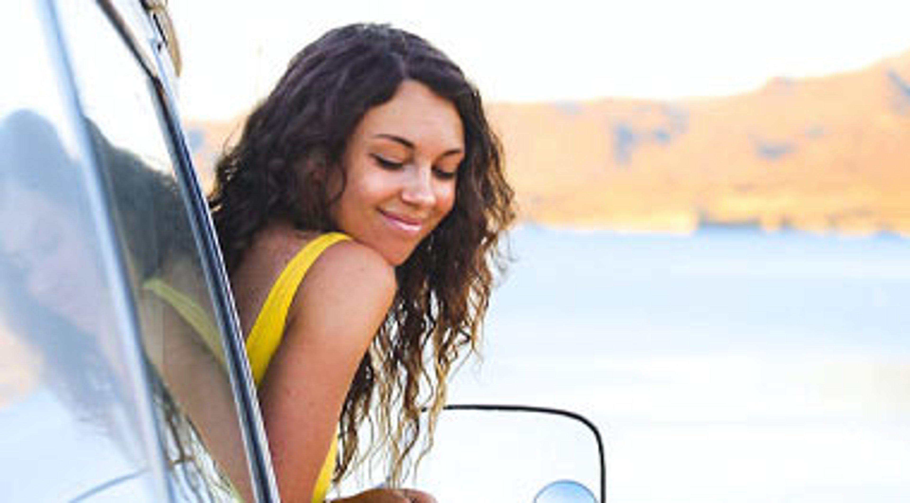 Woman leaning out of window of vehicle with water in the background