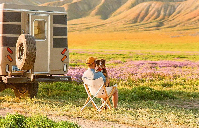 man sitting outside RV with dog