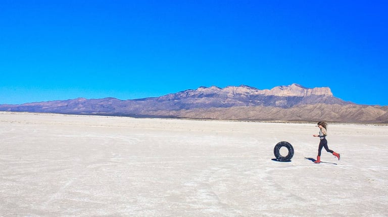 Woman rolling a tire in an open area