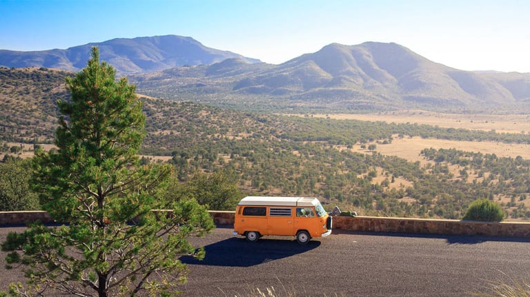 Van sitting along side of road with mountains in the background