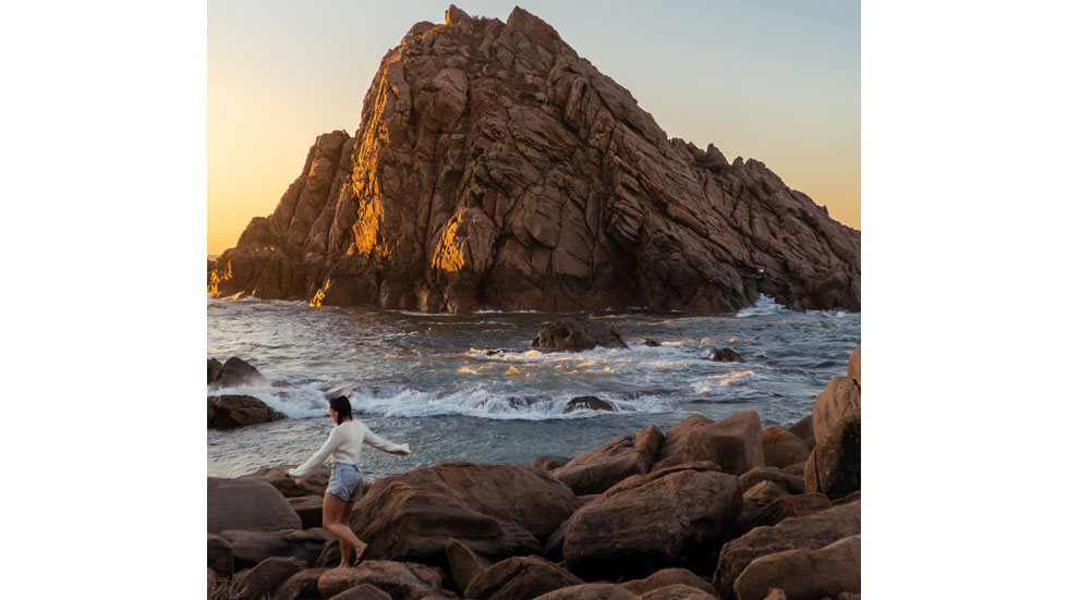 Woman walking over rocks near the water