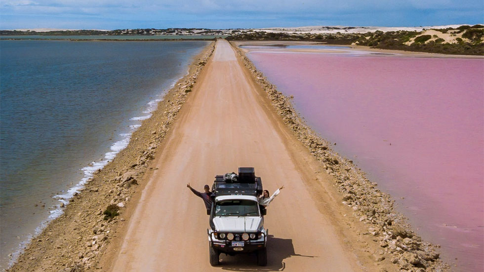 Jeep driving down a road by the ocean