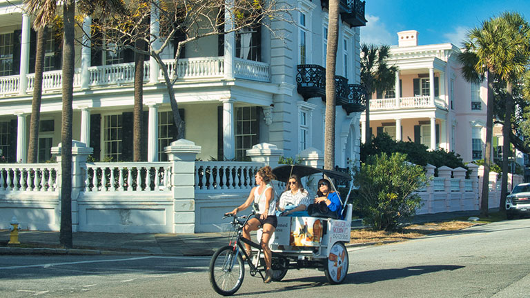 charleston, united states - november 7 2022: old historic houses with colorful facades around small streets and bicycle taxi with people on it Credit:oliver de la haye