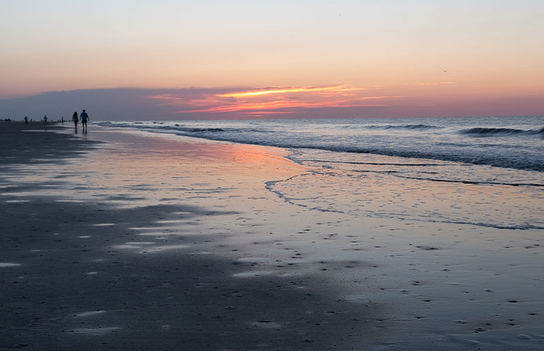 Couple walking at sunrise on Coligny Beach, Hilton Head Island, South Carolina