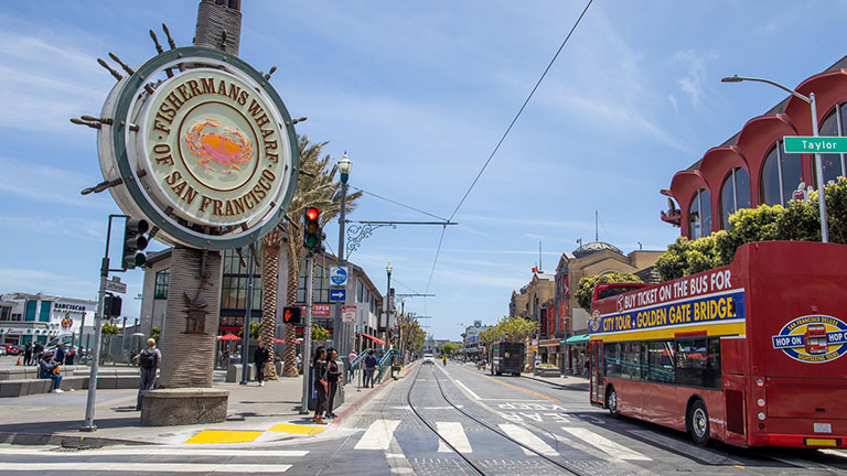 The iconic Fisherman’s Wharf sign overlooking cable tracks, seafood stalls, and the bustle of the waterfront; photo courtesy of San Francisco Travel