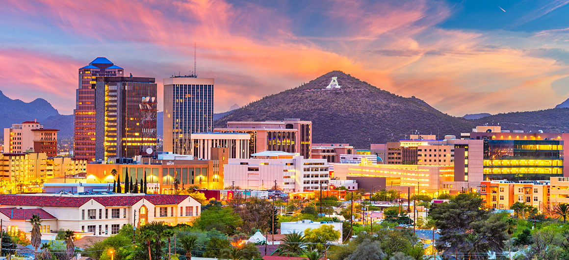 Downtown Tucson skyline glowing at sunset with Sentinel Peak and the illuminated “A” mountain in the background