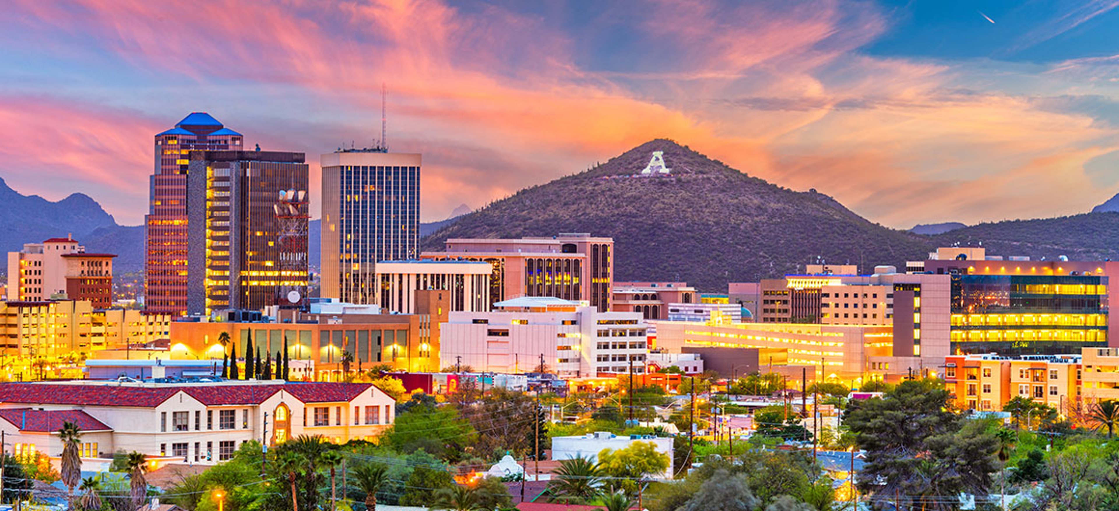 Downtown Tucson skyline glowing at sunset with Sentinel Peak and the illuminated “A” mountain in the background