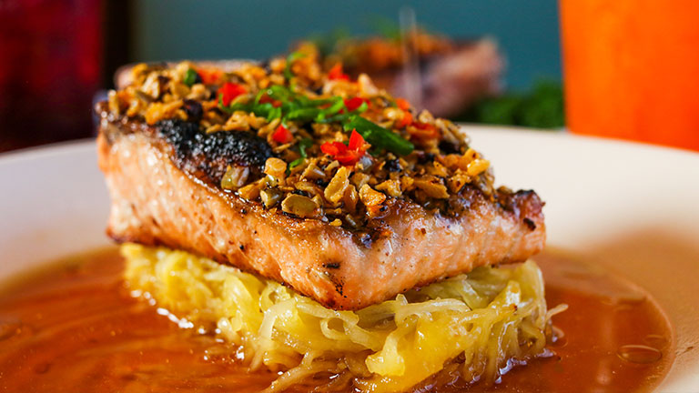Grilled salmon fillet topped with vegetables and served over squash noodles