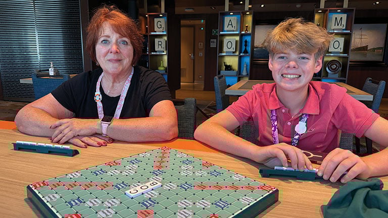 Two guests enjoy a game of Scrabble in a cozy onboard lounge; photo courtesy of Holland America Line