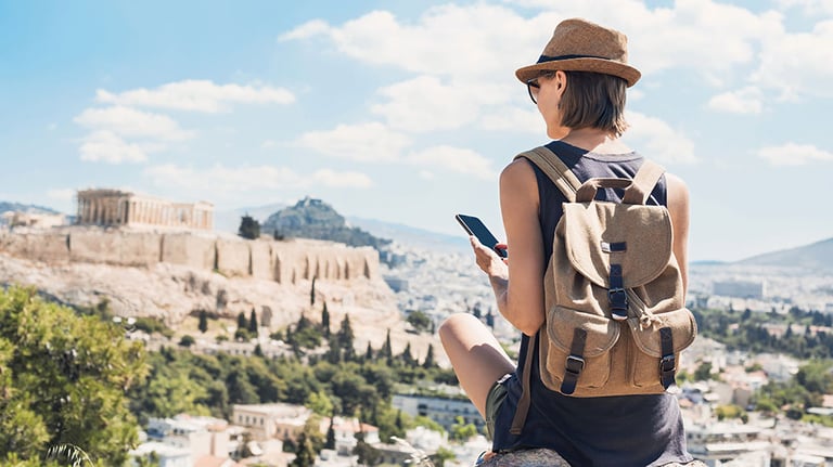 Young woman using smart phone in Athens with Acropolis at the background. Traveler girl enjoying vacation in Greece. Summer holidays, vacations, travel, tourism, technology concept. See Less by kite_rin