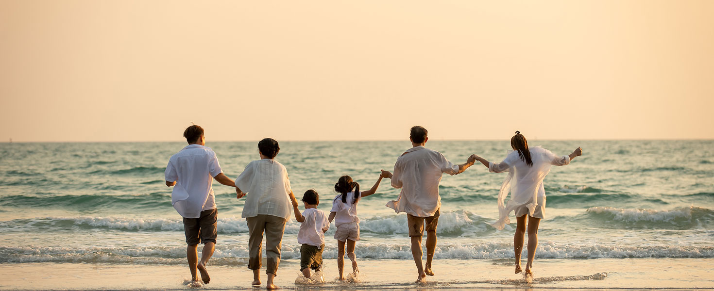 Multigenerational family on beach, holding hands