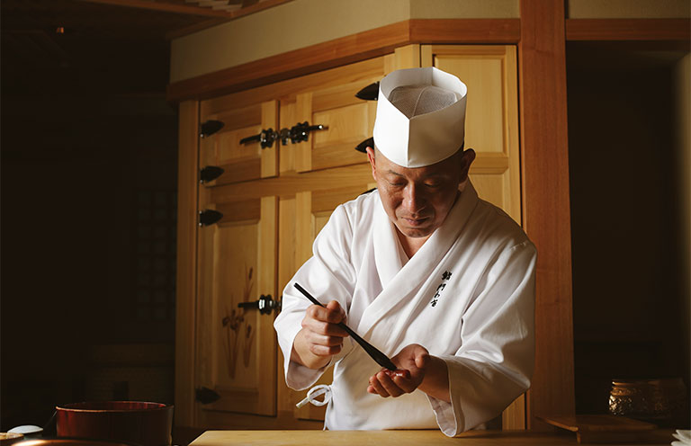 A chef at Sushi Kadowaki, an intimate Ginza counter serving a seasonal omakase tasting menu; tender abalone in a sauce enriched with abalone liver from Sushi Kadowaki.