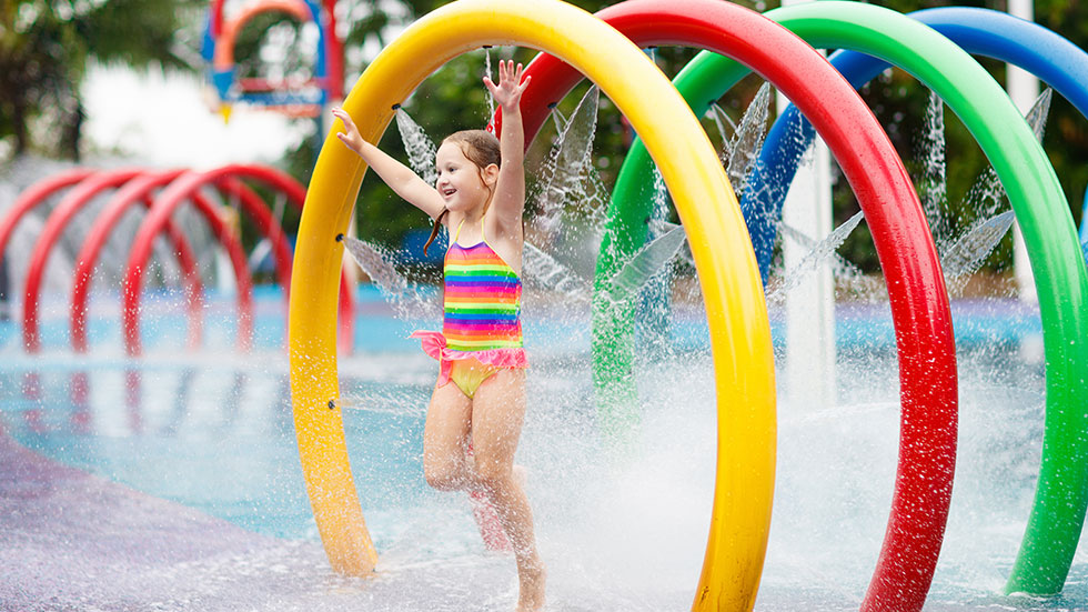 Little girl running through water park sprinkler