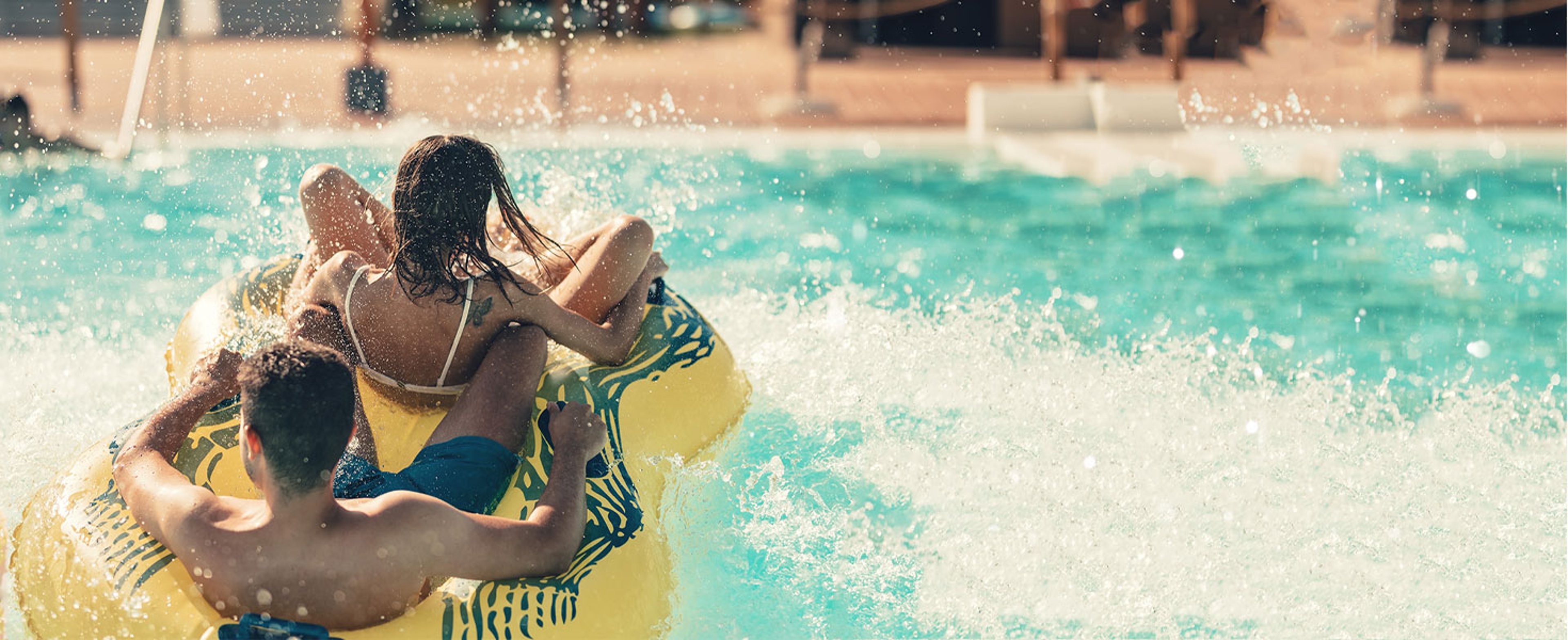 Couple going down water slide in double tube