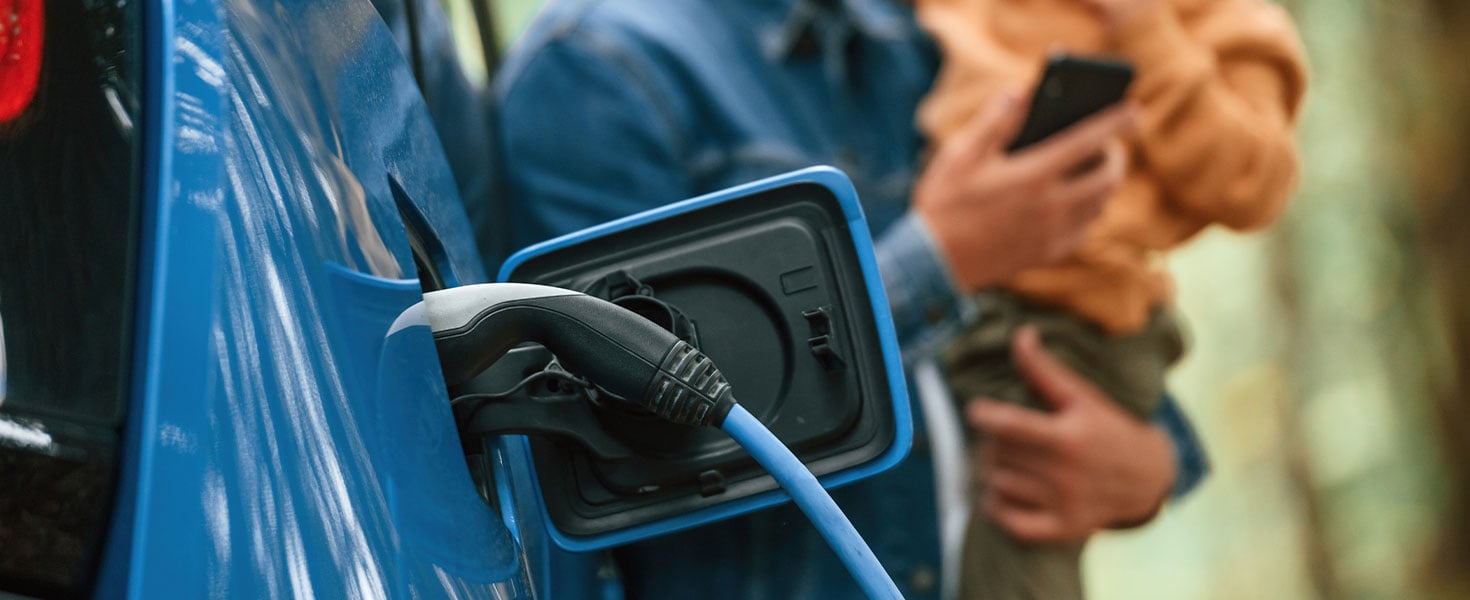 electric vehicle charging, man holding child in background