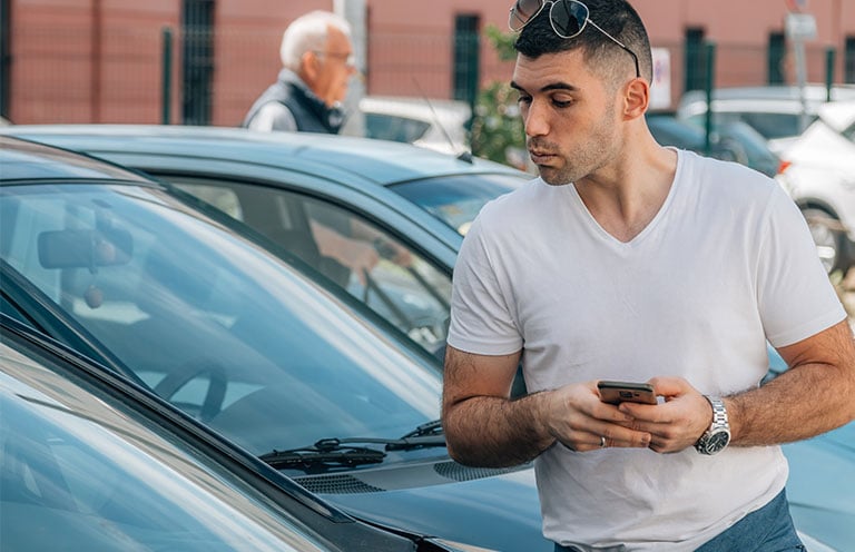 man looking at parked car
