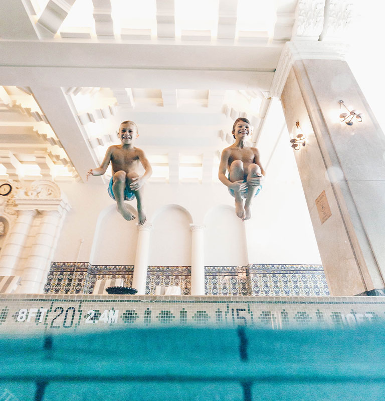 two boys jumping into pool
