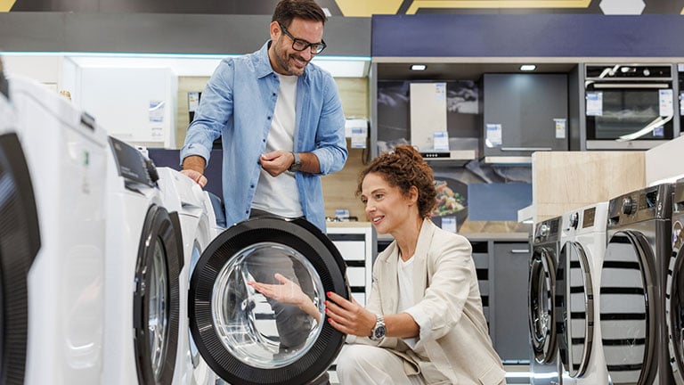 Mid adult couple shopping for a new washing machine at the appliance store stock photo