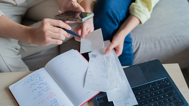 Close-up photo of husband and wife hands doing financial planning and checking receipts at home stock photo 