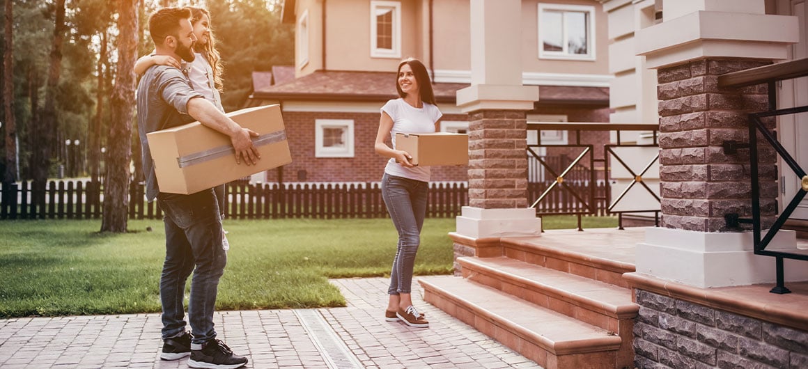 man and woman moving into house, holding boxes