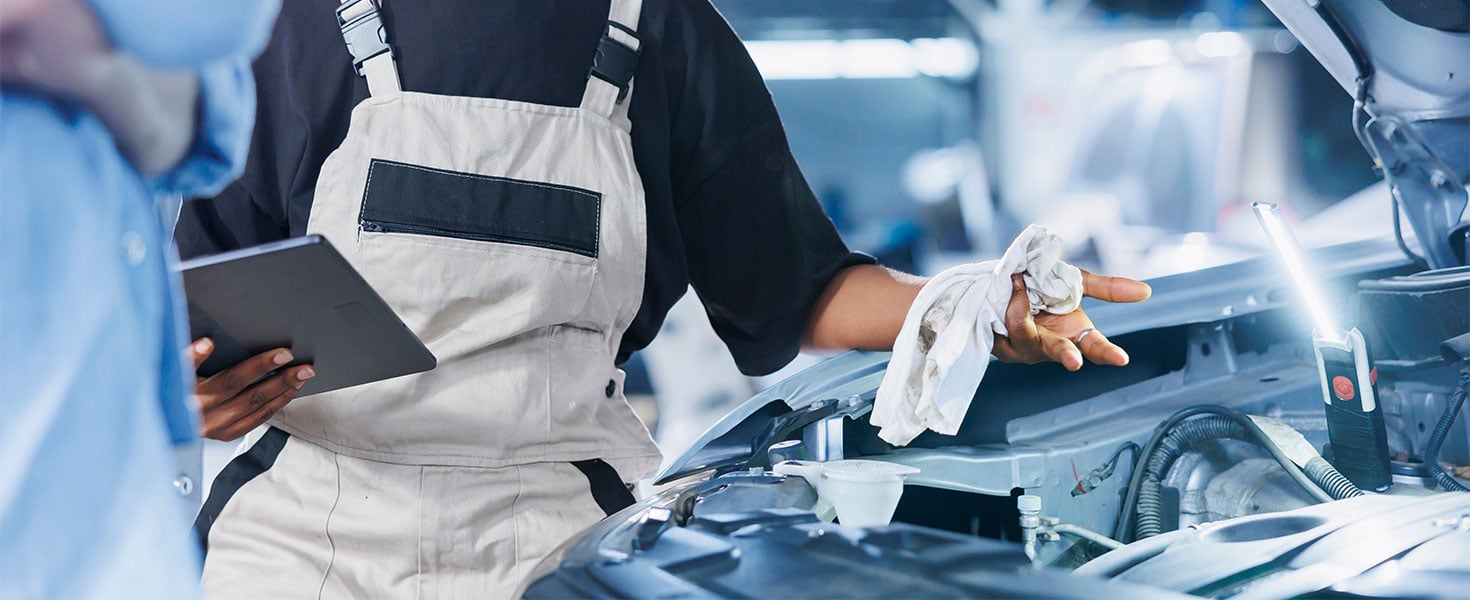 mechanic looking showing customer under car hood