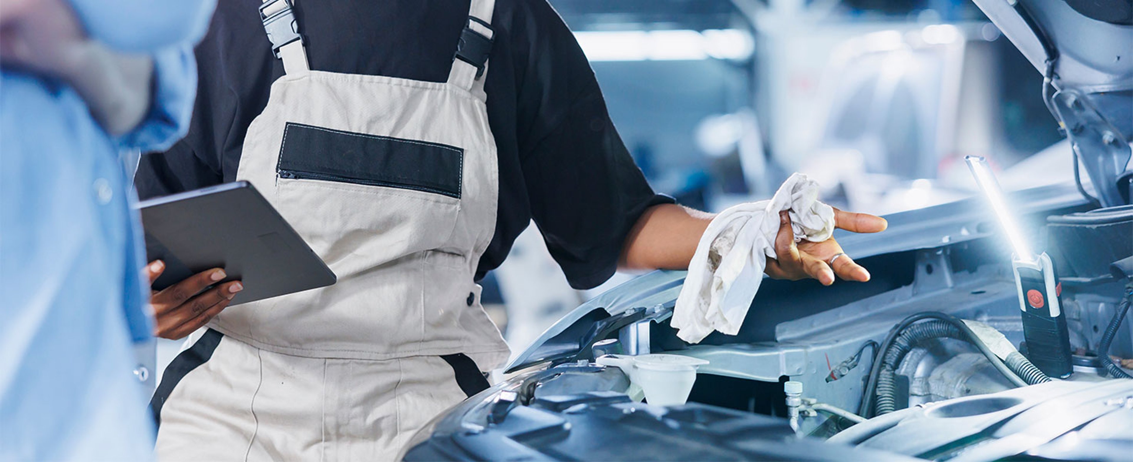 mechanic looking showing customer under car hood