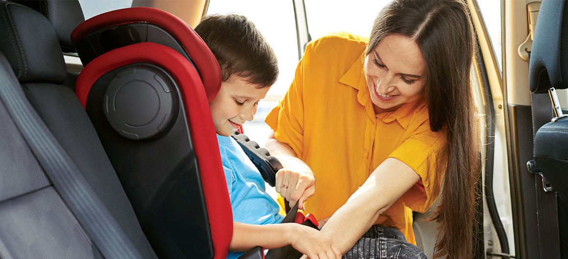 mom fastening kid into car seat