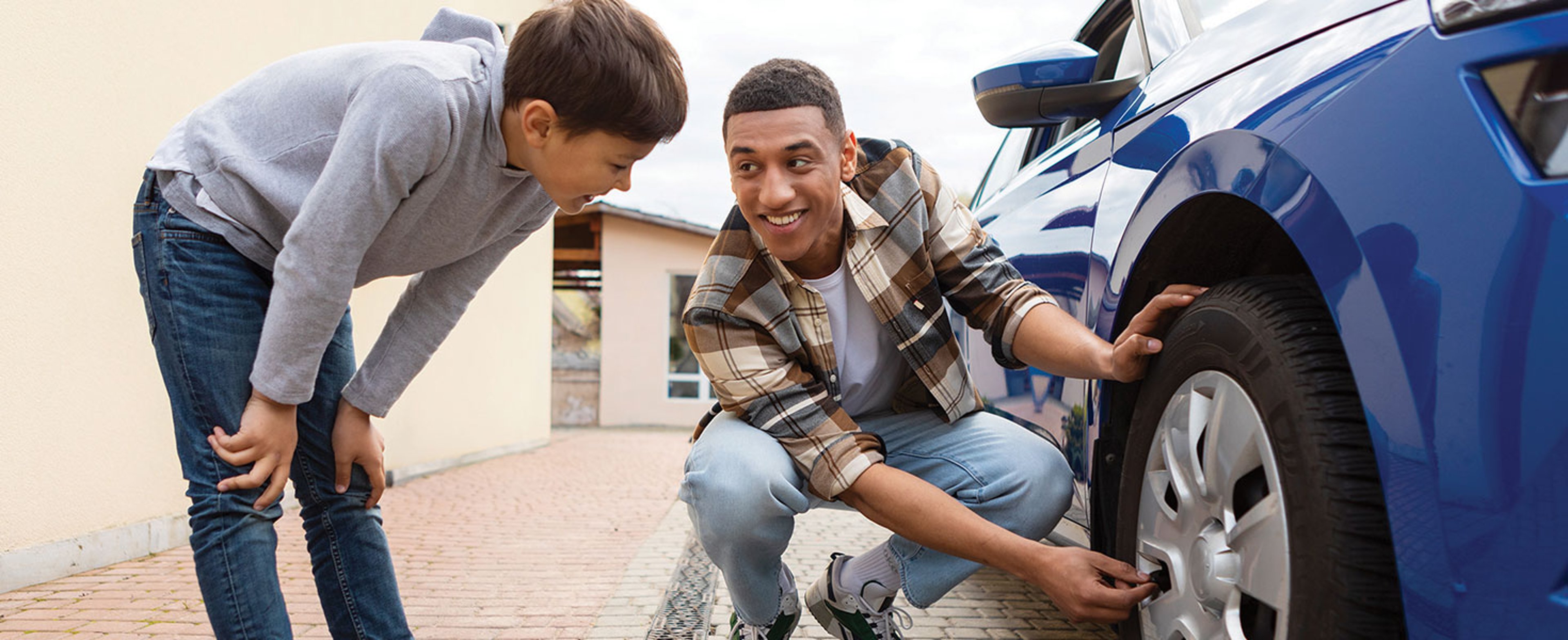 Father and his son checking wheel together on summer day. Family of two repairing automobile. by Home-stock