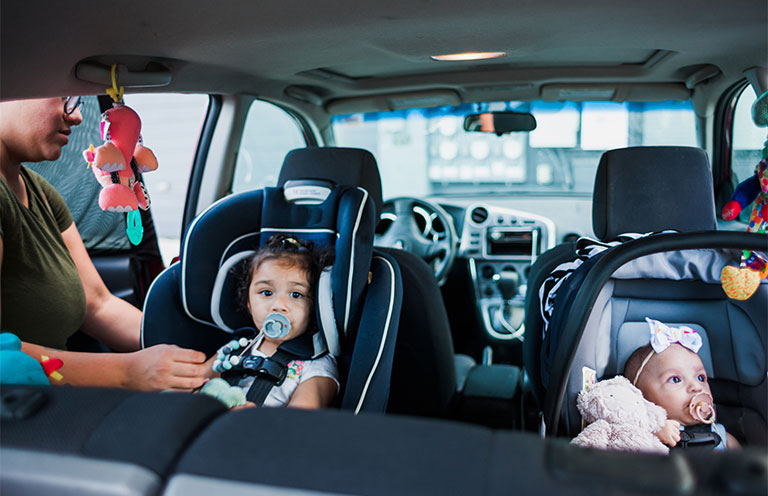 mom buckling babies into car seats