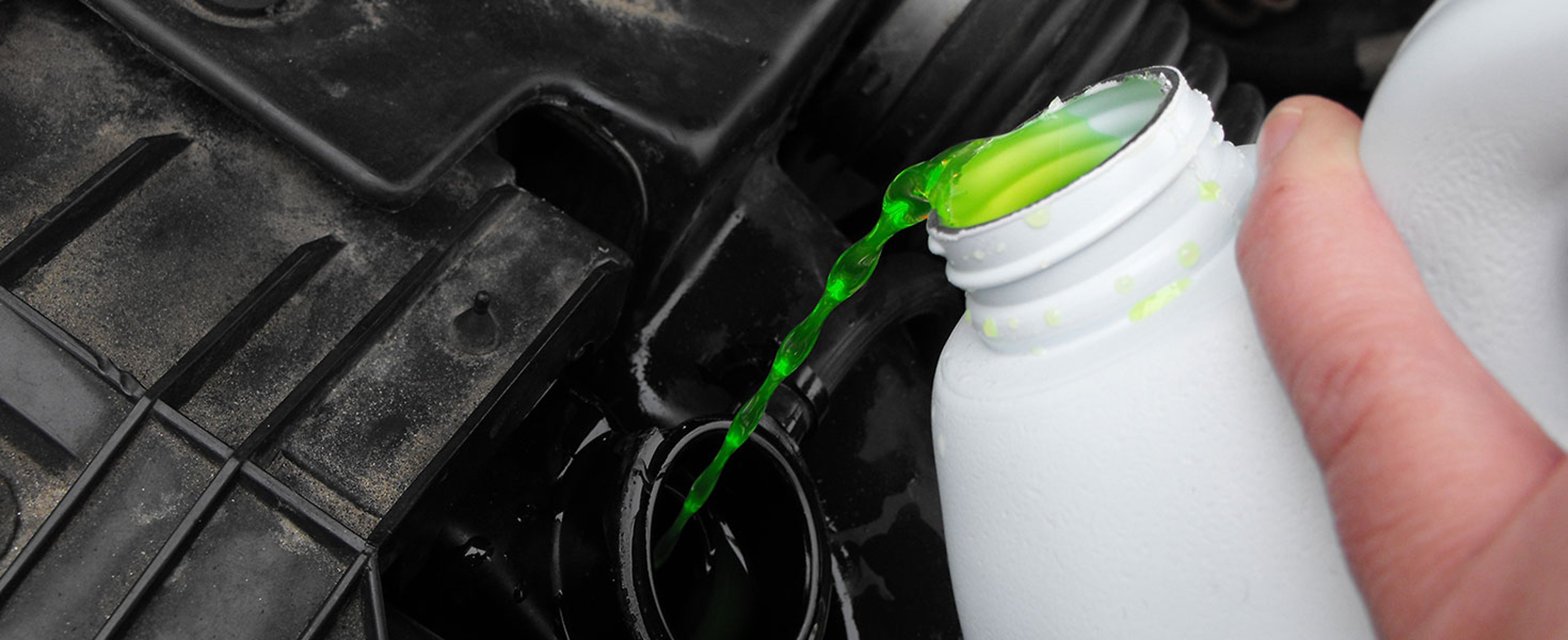 Pouring flourescent green antifreeze into a black engine