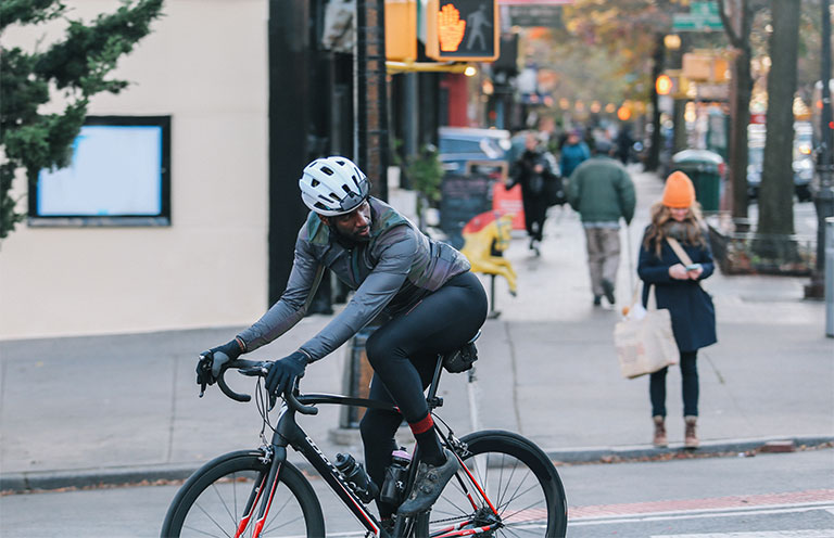 man riding ebike on street, looking over shoulder as he merges