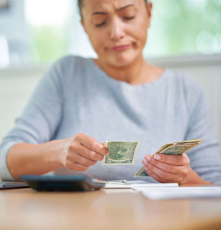 Young woman counting home budget with bills; Credit:macniak
