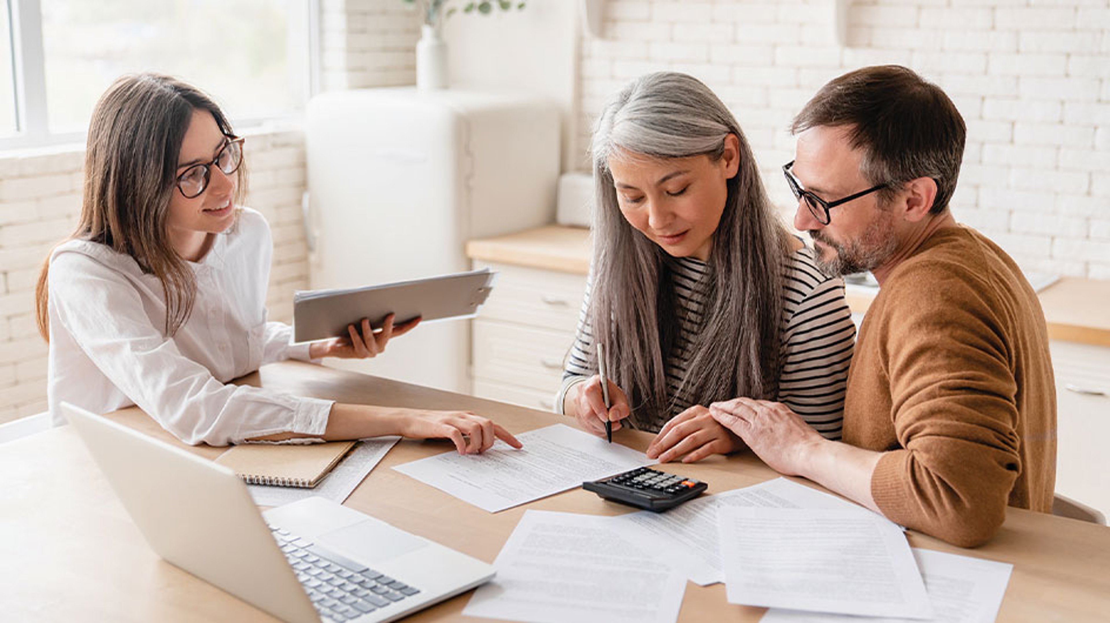 woman pointing at documents on desk in front of couple