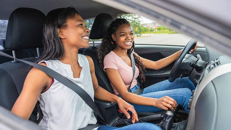 Young black teenage driver seated in her new car with her mother; By Louis-Photo