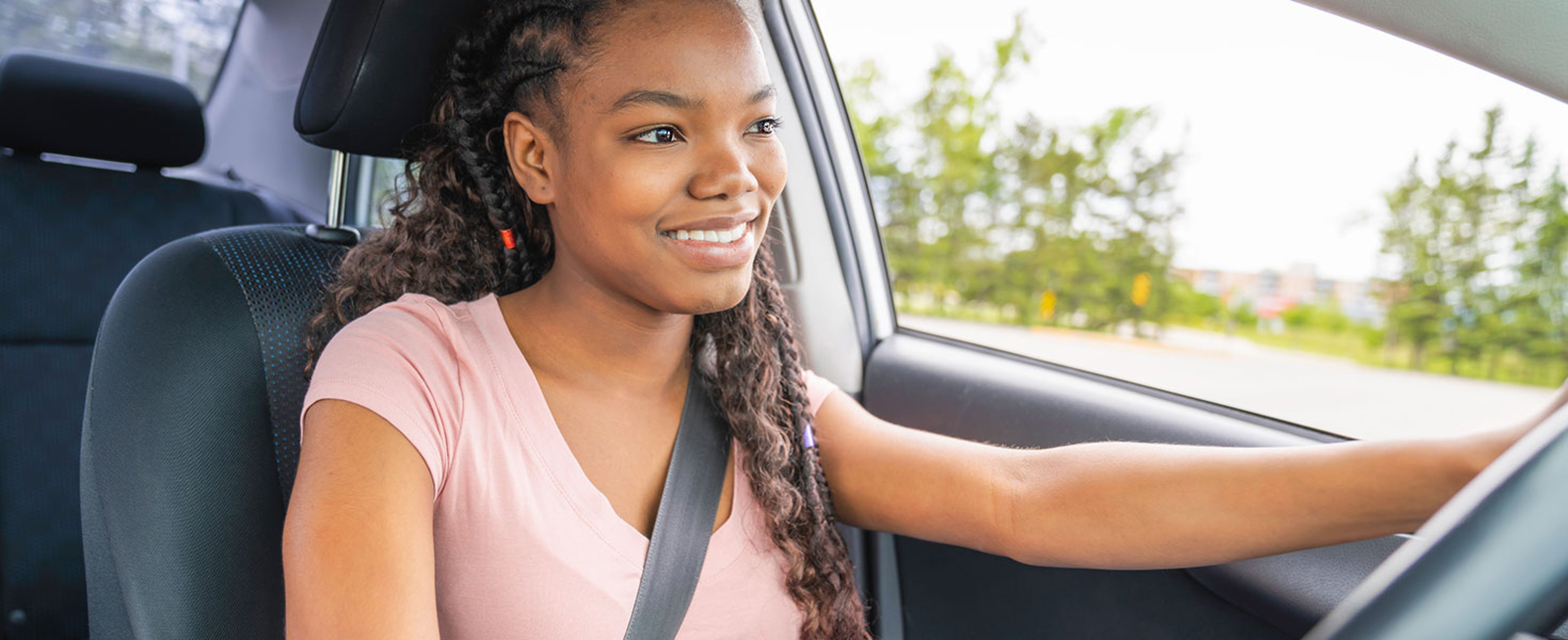 Young black teenage driver seated in her new car; by Louis-Photo
