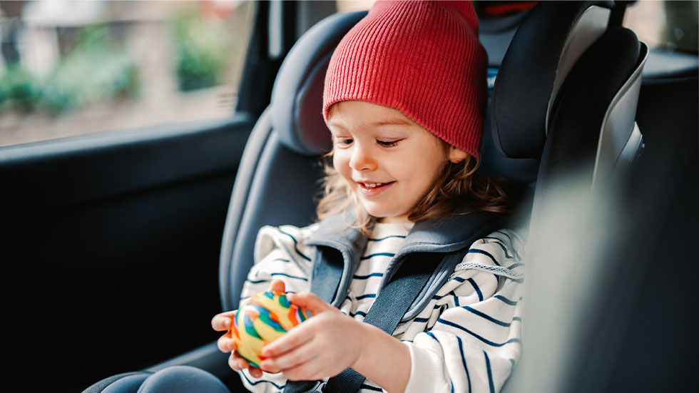 little girl playing with toy in car seat