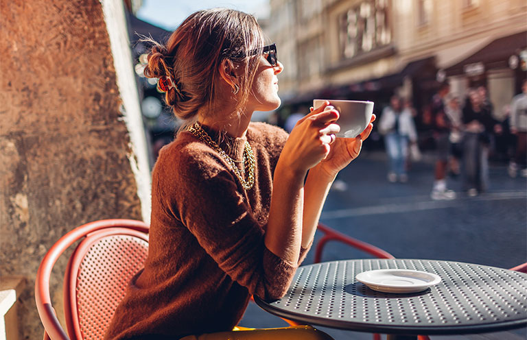 woman drinking coffee at outside cafe