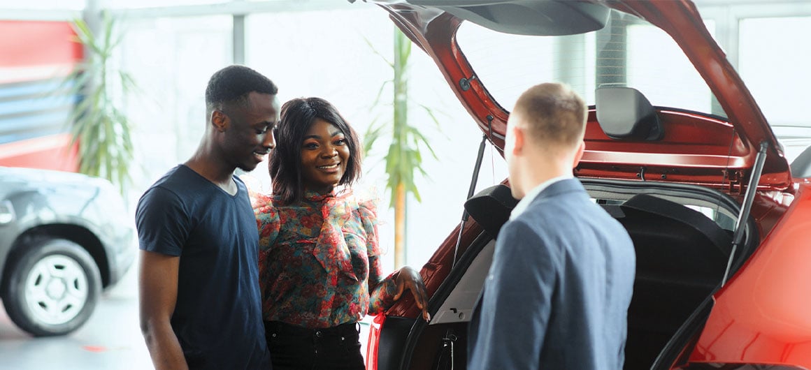 man and woman looking at car with salesman