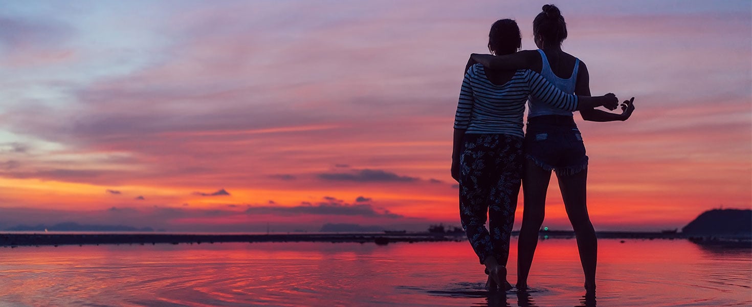 couple walking by water during sunset