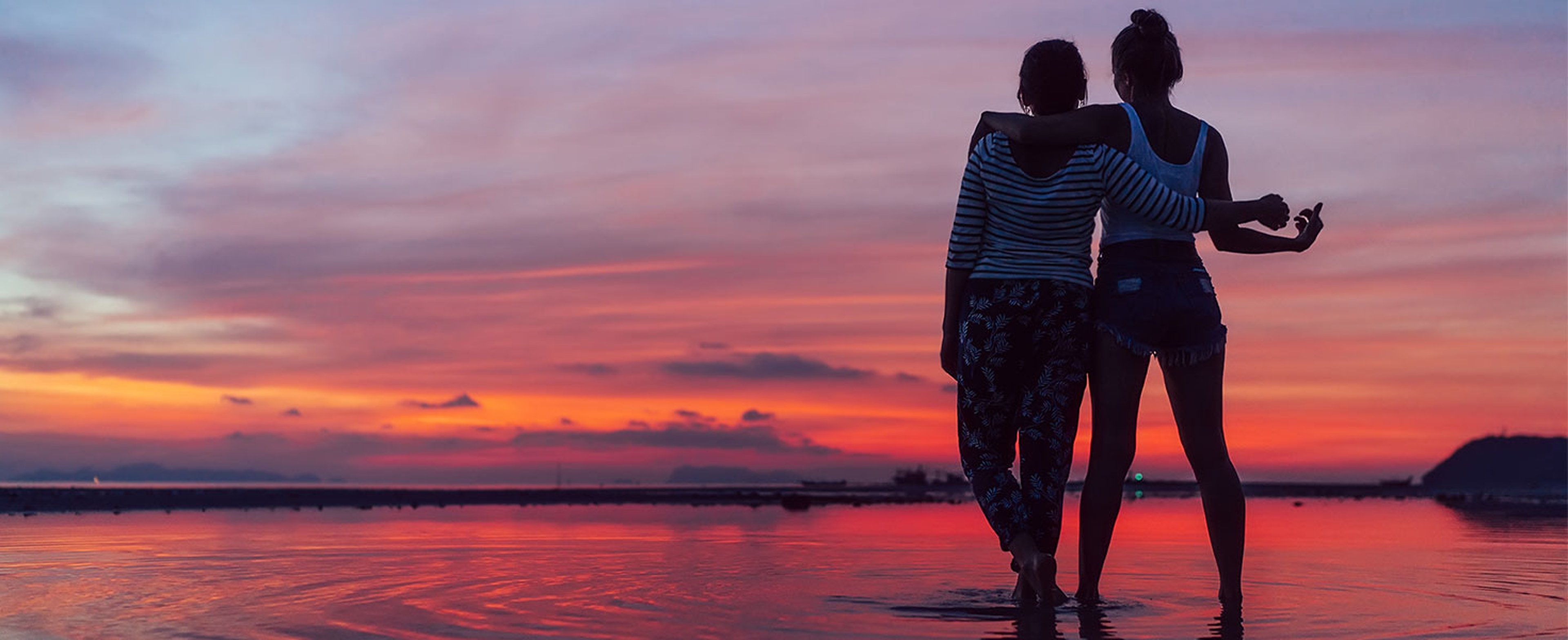 couple walking by water during sunset