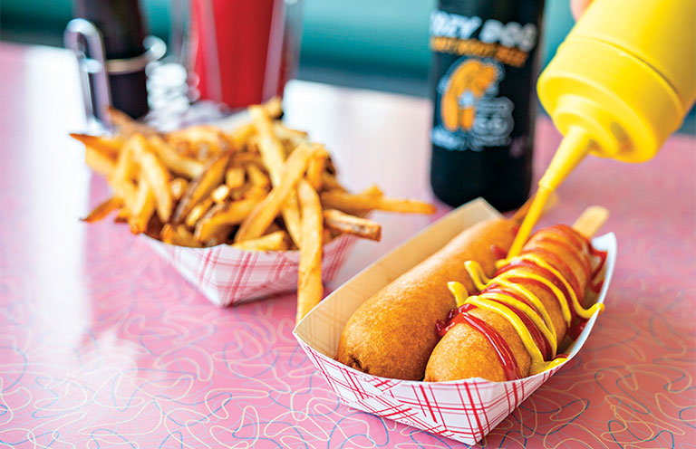 mustard being added to corn dogs from Cozy Dog Drive In