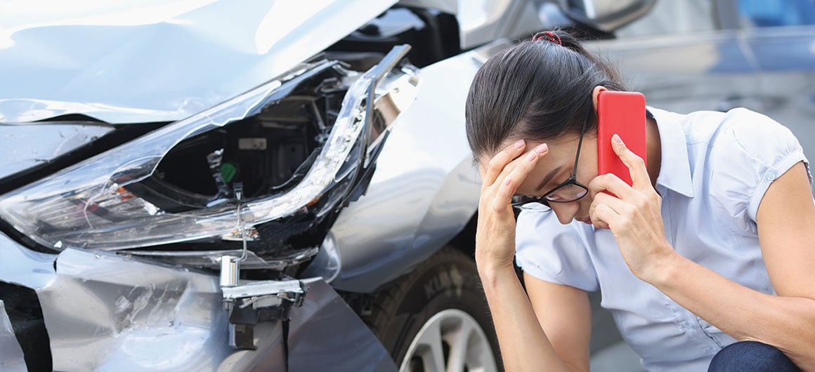 woman on the phone next to crashed car