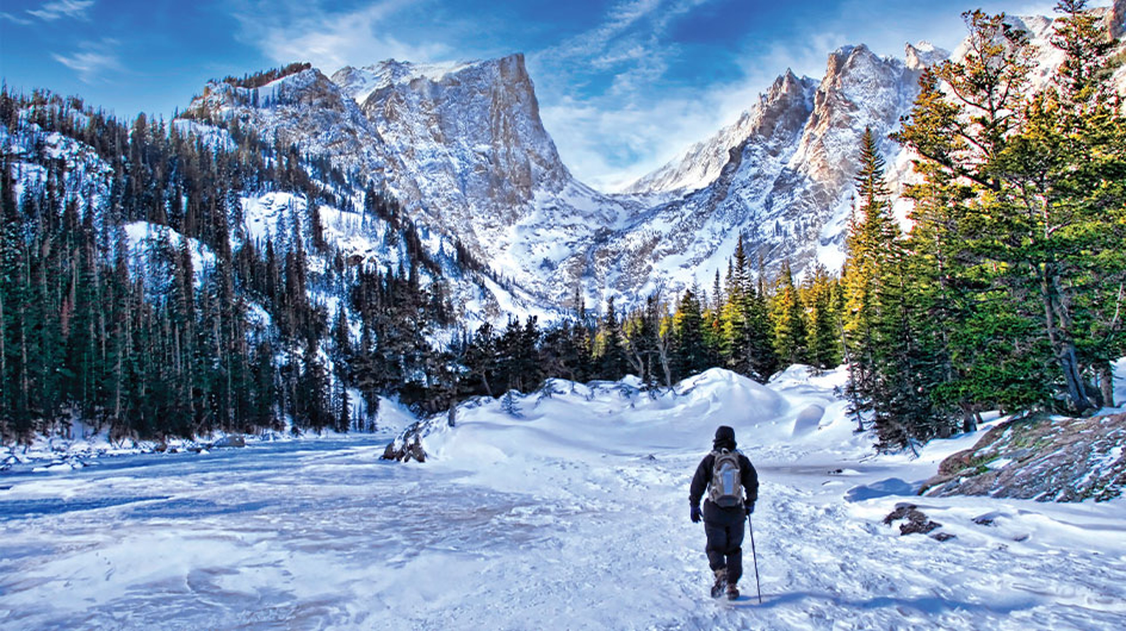 person standing in snow looking out at mountains