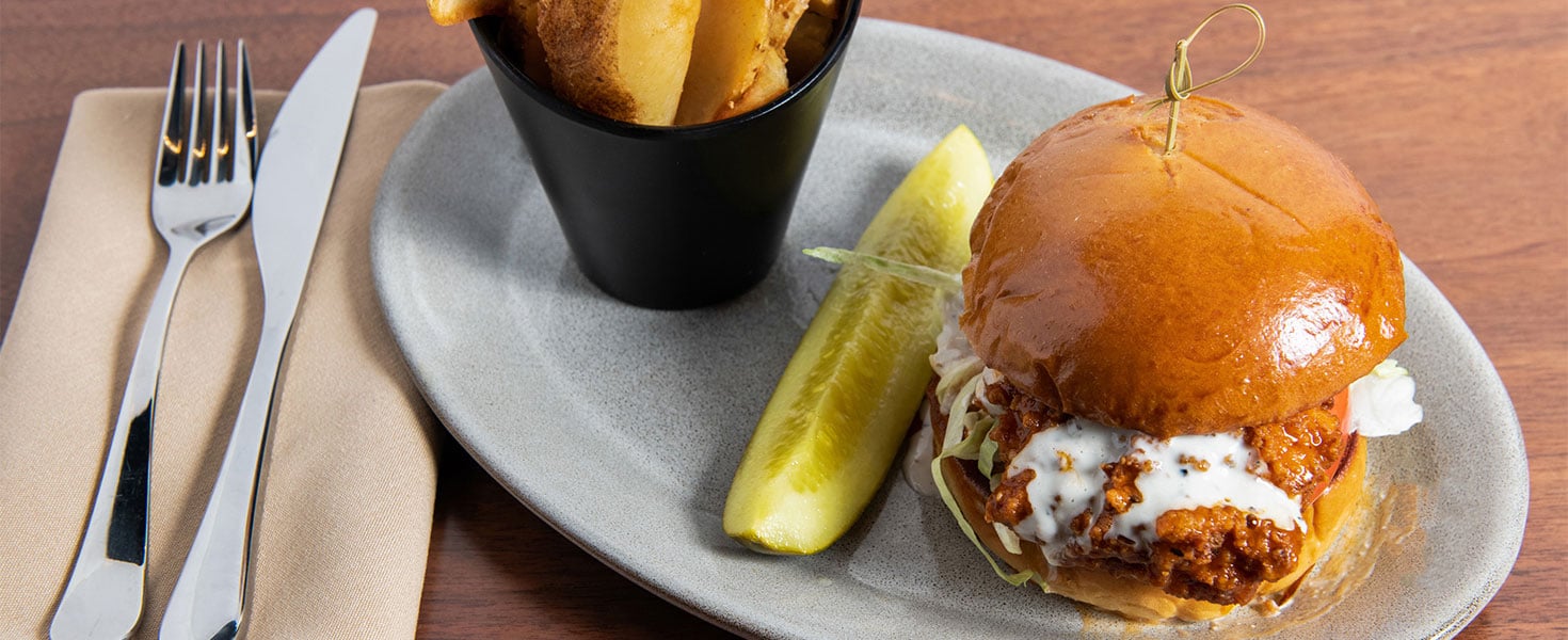 Chicken sandwich on plate with fries and pickle 