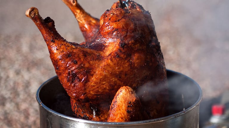 Hot fresh and delicious turkey being removed from a deep fat fryer after being cooked for a holiday celebration. Credit: grandriver