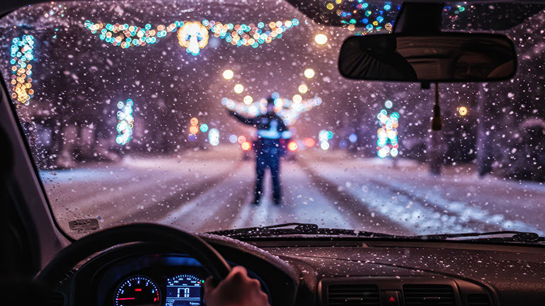 Police officer directing traffic in snowy city at night By stock.metket.com