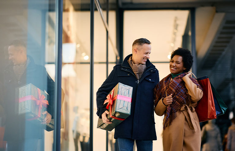 people holding gifts walking out store