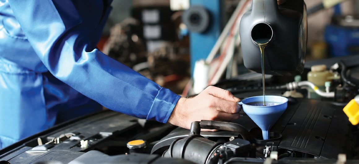 man adding oil to car engine