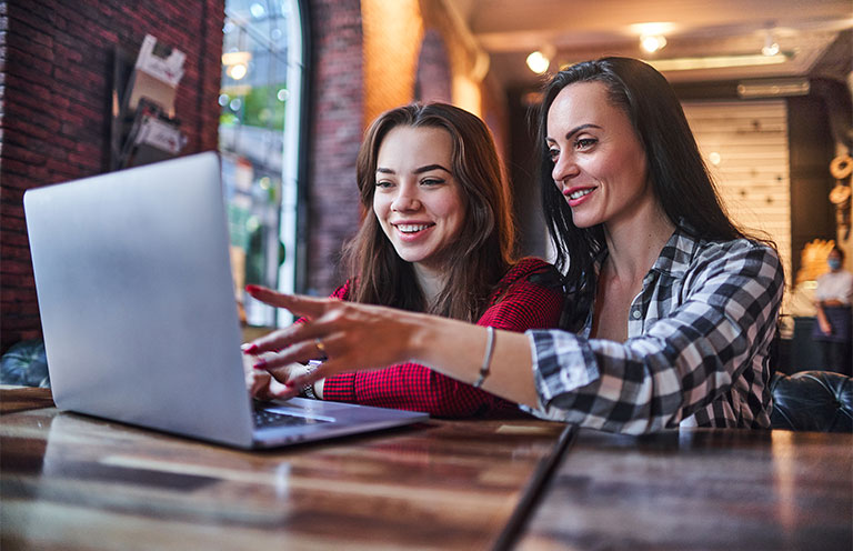 mother and daughter using laptop looking happy